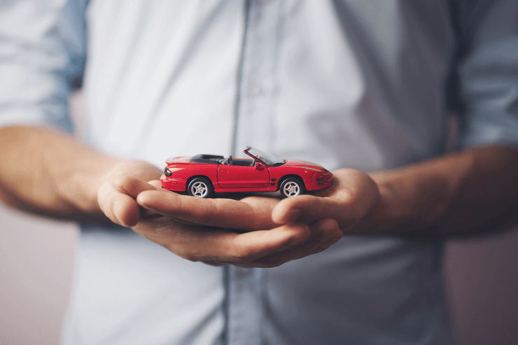 A man with a small car figure in his hands